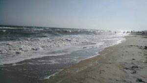 Sunny beach with gentle waves and sand.